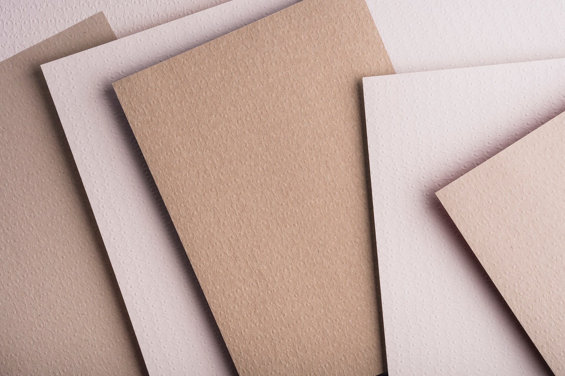 Ark av kartong i grå och beige toner som ligger omlott på varandra